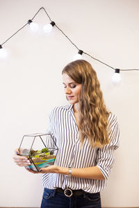 Young woman smiling while standing against glass