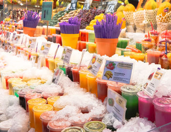 Various fruits and smoothies slices in disposable glasses for sale at shop