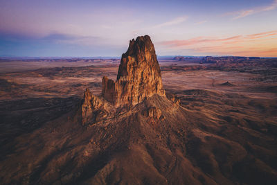 Rock formation on landscape against sky during sunset