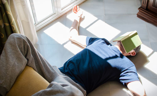 High angle view of man sitting on book at home