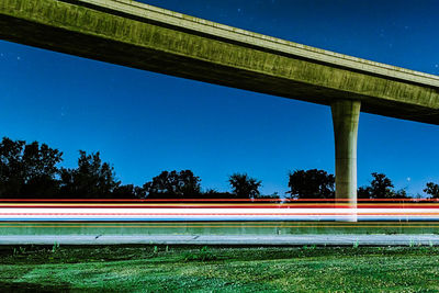 Bridge over road against clear blue sky