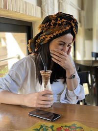 Portrait of young woman sitting on table laughing