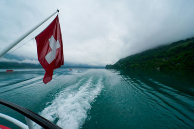 Scenic view of red flag on sea against sky
