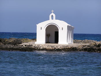 Church by sea against clear blue sky