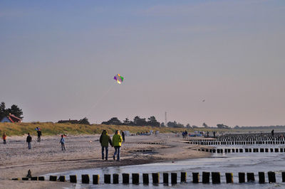 People at beach against clear sky