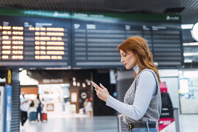 Woman using smart phone at airport