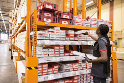 Saleswoman arranging merchandise in rack at hardware store