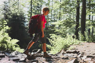 Woman with backpack hiking in mountains, spending summer vacation close to nature