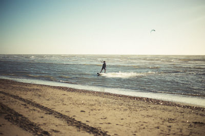 Silhouette people on calm beach against clear sky