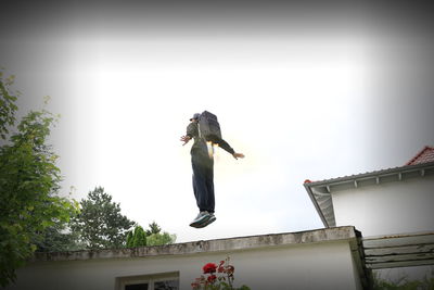 Low angle view of person jumping against clear sky