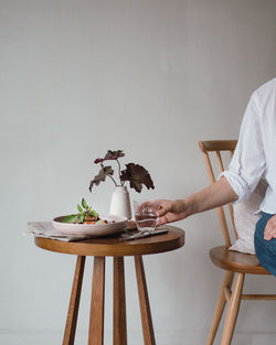 Woman holding drinking glass on wooden table at home