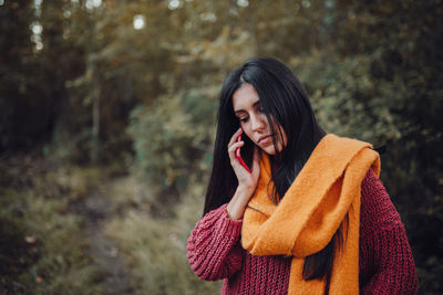 Young woman looking away while standing in forest