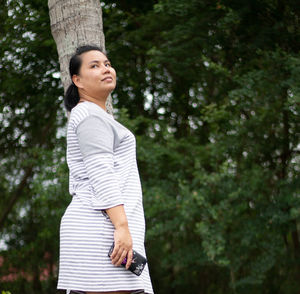 Side view of woman standing on tree trunk