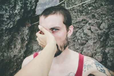 Cropped hand of woman covering man face against wall