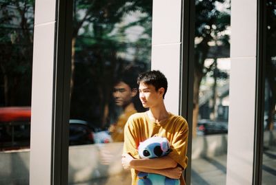 Young man standing by window