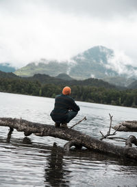 Rear view of man on lake against mountain range