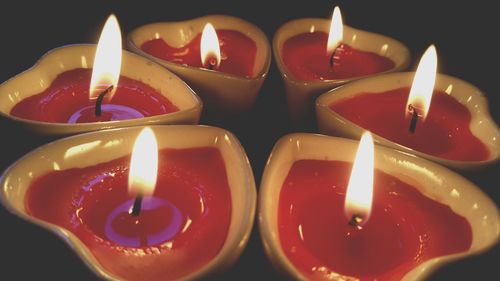 Close-up of heart shape tea light candles burning against black background