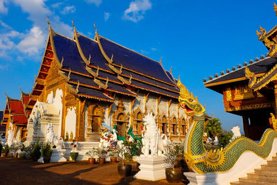 Statues on field by temple against sky