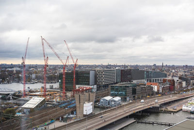 High angle view of cranes and buildings in city against sky