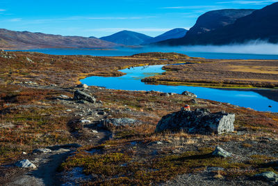 Scenic view of lake and mountains against blue sky