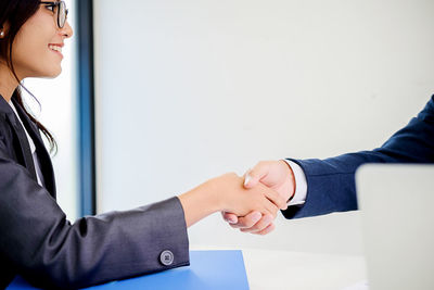 Cropped hand businessman shaking hands with female colleague in office