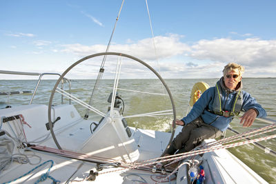 Portrait of smiling man sitting on boat against sky