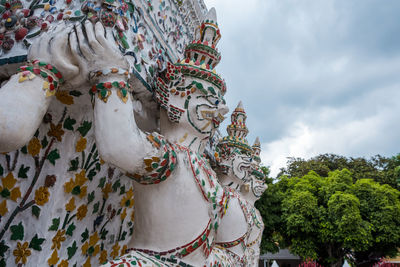 Statue at wat arun ratchavararam, river side temple with a landmark spire.