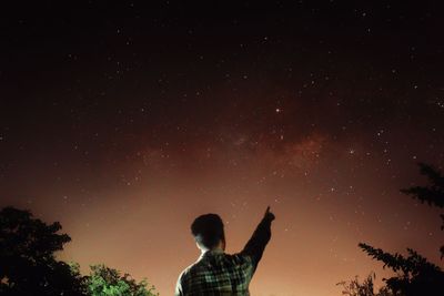 Low angle view of silhouette man standing against sky at night