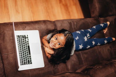 Mixed race young girl at home on the sofa using a laptop computer for learning