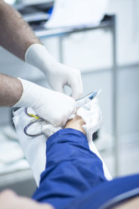 Midsection of doctor removing orthopedic cast from patient leg