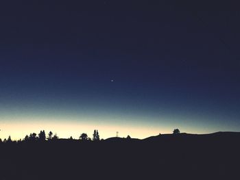 Silhouette landscape against clear sky at night