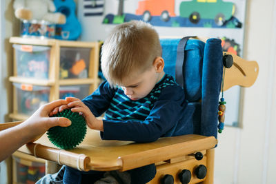 Boy holding toy sitting at home