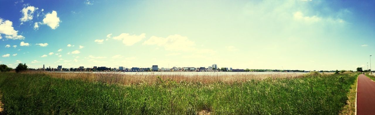 grass, sky, field, blue, building exterior, built structure, cloud - sky, architecture, landscape, tranquil scene, cloud, green color, tranquility, growth, panoramic, nature, scenics, beauty in nature, plant, grassy