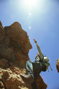 Low angle view of person on rock against sky