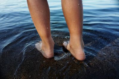 Low section of child standing at beach