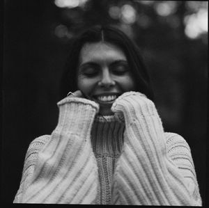 Portrait of young woman standing against black background