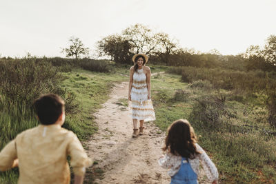 Young mother standing in field waiting for children to run to her