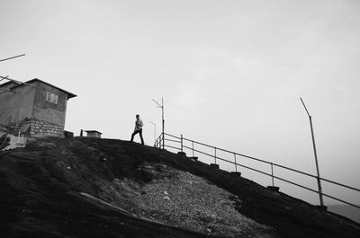 Low angle view of men standing on building against clear sky