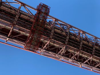 Low angle view of crane against clear blue sky