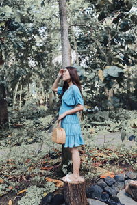 Full length of woman standing by tree in forest