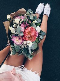 Low section of woman holding bouquet