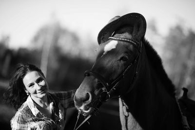 Portrait of mid adult woman standing by horse in barn