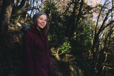Portrait of smiling woman standing at forest