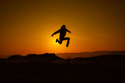 Silhouette man jumping on orange sky during sunset