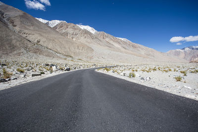 Road leading towards mountains against sky