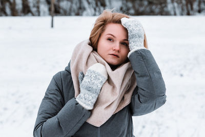 Portrait of young woman standing on snow covered field