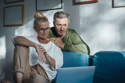 Couple watching laptop on sofa at home