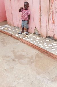 Rear view of boy standing against wall