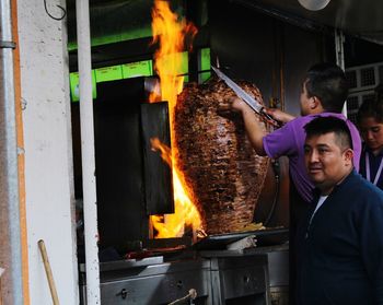 Man standing with meat on barbecue grill