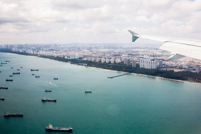 Aerial view of city by sea against sky